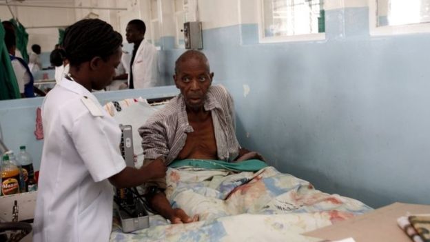 An elderly patient receives treatment from a nurse while sitting up in bed at Harare central hospital (28 February 2009)