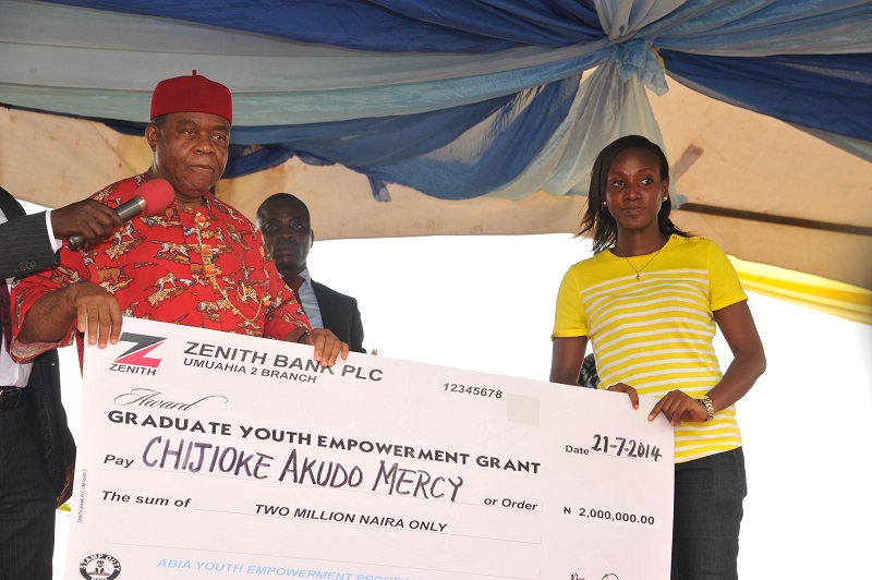 Abia state governor, Theodore Orji presenting cheques to some of the beneficiaries as part of their empowerment during the 2014 youth empowerment programme for Arochukwu, Ohafia and Bende at Bende Local Government headquaters in Bende LGA