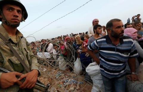 A Turkish soldier stands guard as Syrian Kurdish refugees wait behind the border fences to cross into Turkey near the southeastern town of Suruc in Sanliurfa province September 27, 2014. REUTERS/Murad Sezer