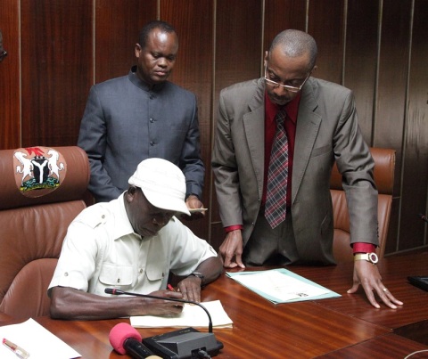 Governor Adams Eric Oshiomhole signs the Edo State 2015 Appropriation Bill into Law watched by the Commissioner for Budget and Economic Planning, Hon Lawrence Aghedo (2nd right) and Rt Hon Uyi Igbe, Speaker, Edo State House of Assembly (right).