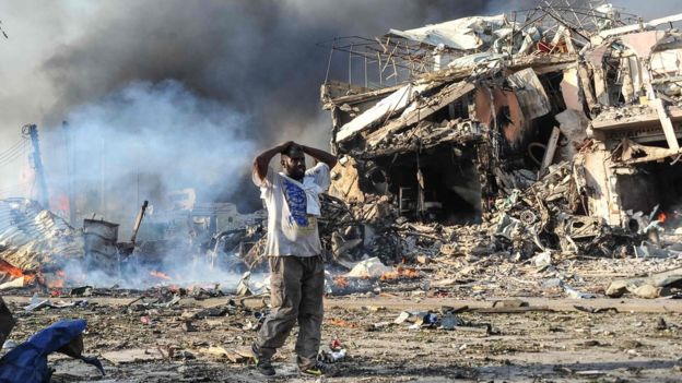 A Somali man reacts next to a dead body on the site where a car bomb exploded at the center of Mogadishu, on October 14, 2017