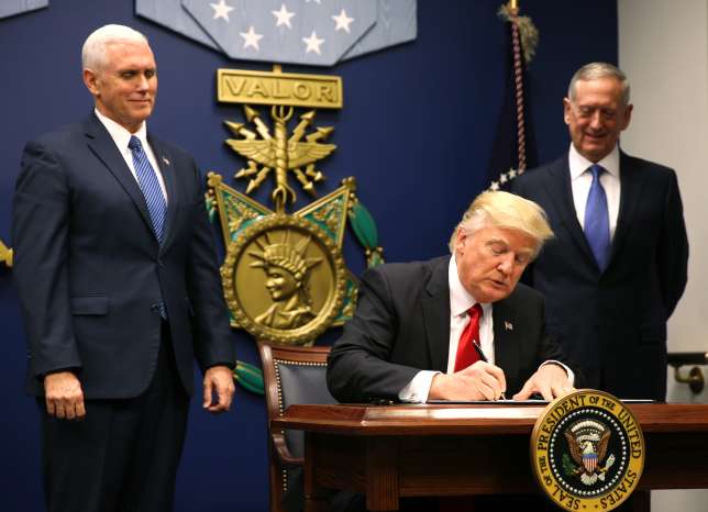 U.S. President Donald Trump (C) signs an Executive Order establishing extreme vetting of people coming to the United States after attending a swearing-in ceremony for Defense Secretary James Mattis (R) with Vice President Mike Pence at the Pentagon in Washington, U.S., January 27, 2017.