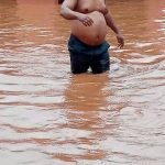 Man wading through a flooded compound in Anambra